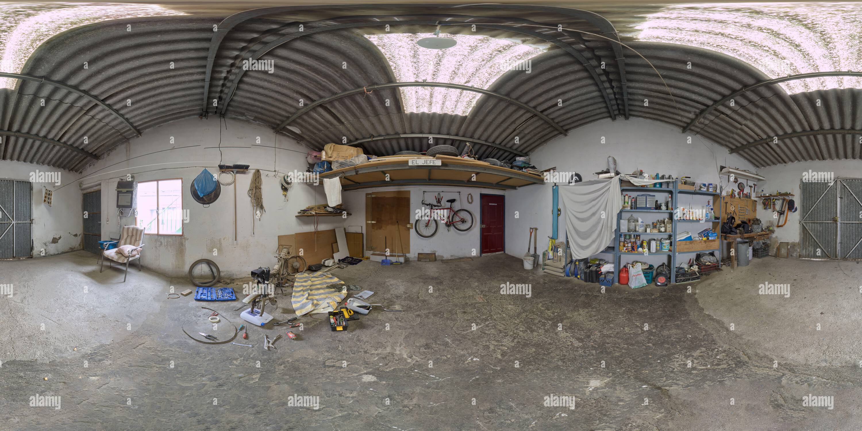 360 degree panoramic view of Panoramic 360 degree photograph of a garage with a motorcycle disassembled to fix it.