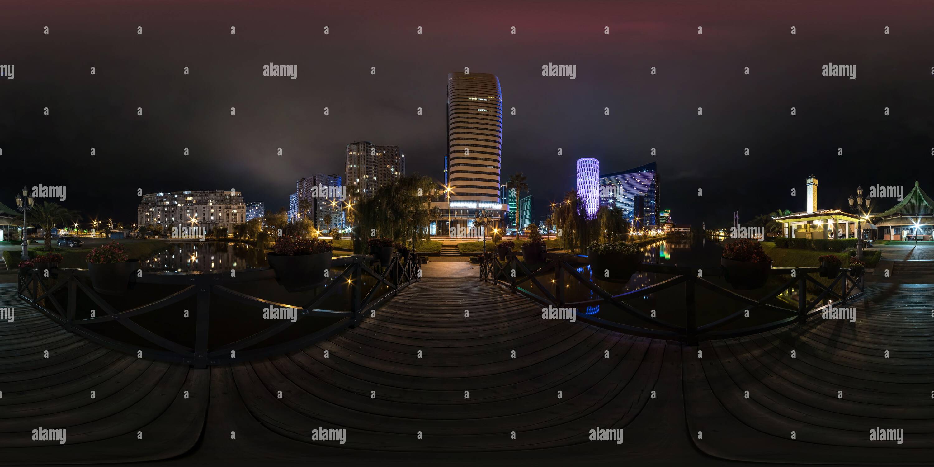 360 degree panoramic view of full seamless spherical night 360 panorama on wooden bridge across river among modern glowing skyscrapers and office buildings in equirectangular proj