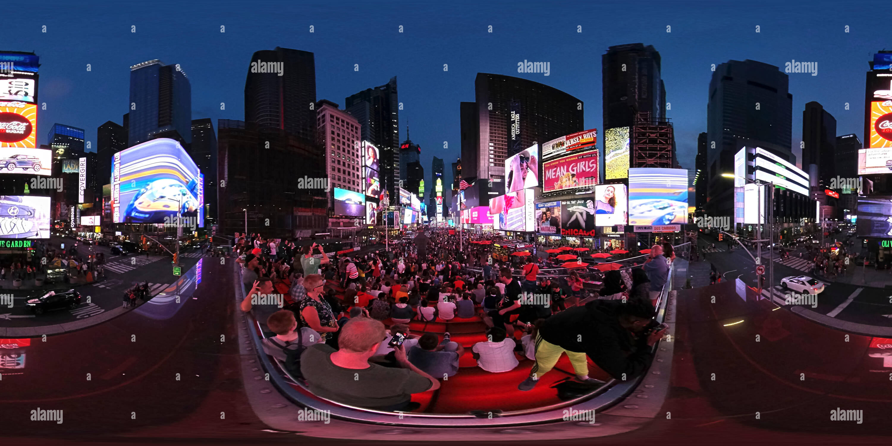 360 degree panoramic view of 360 degrees panorama of Times Square New York at dusk with illuminated advertising boards and tourists taking photos.