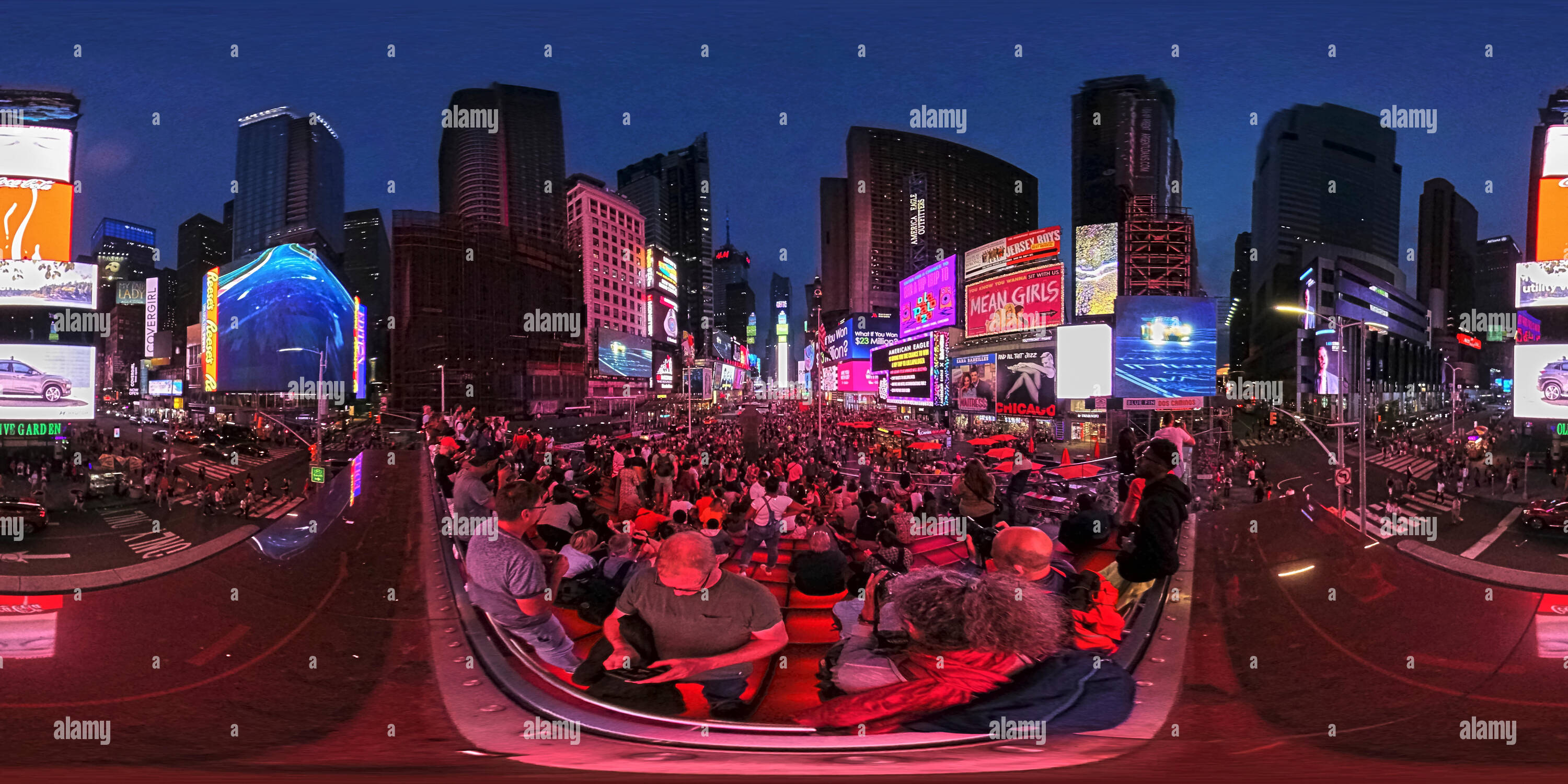 360 degree panoramic view of 360 degrees panorama of Times Square New York at dusk with illuminated advertising boards and tourists taking photos.