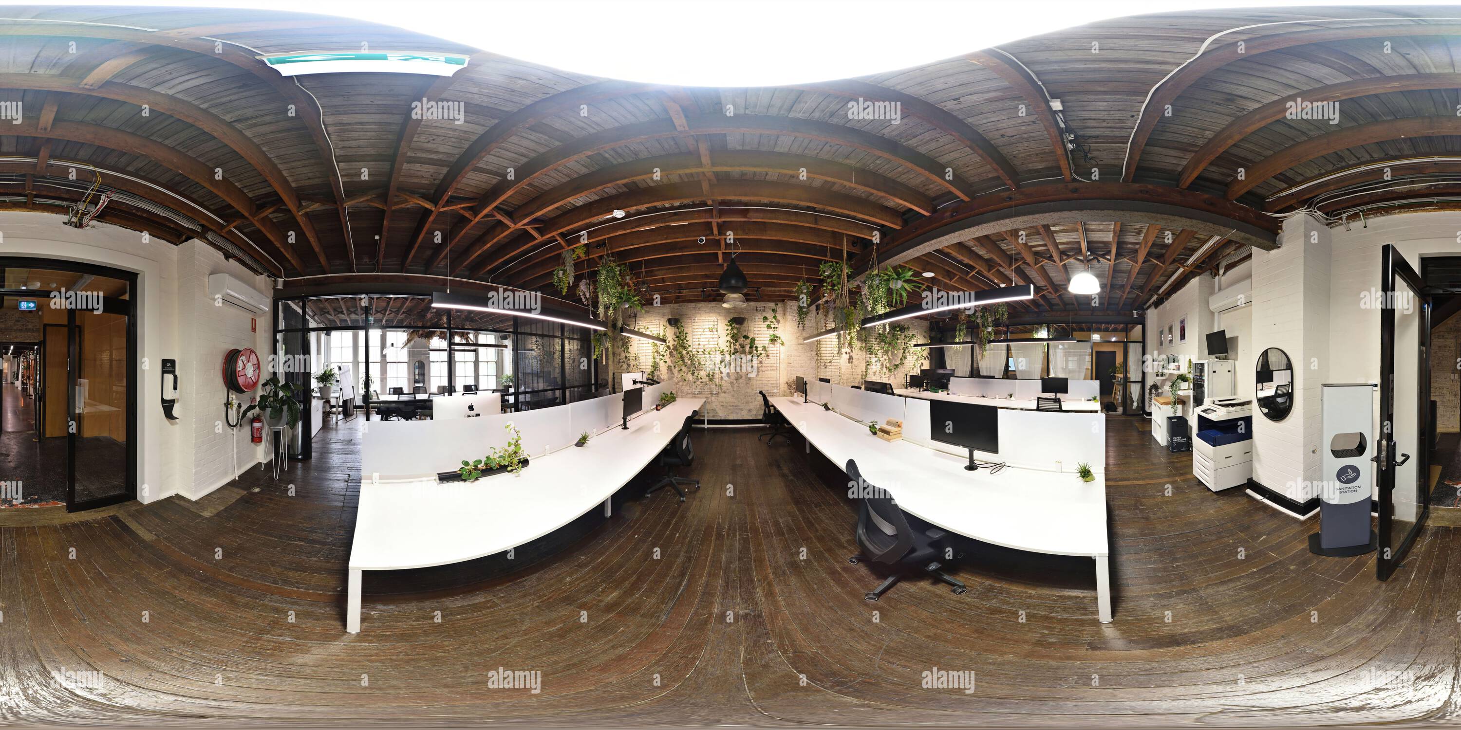 360 Grad Panorama Ansicht von 360°-Panorama eines Bürobereichs im Loft-Stil mit heißem Schreibtisch in einem alten Fabrikgebäude, Holzboden und freiliegender Balkendecke