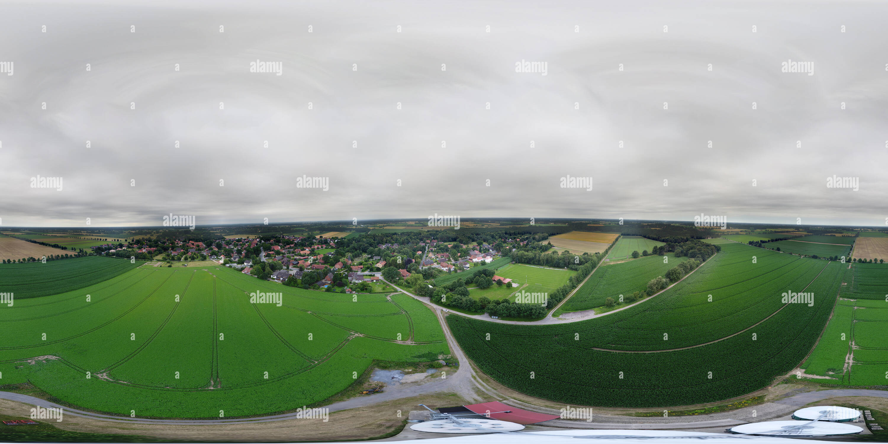 360 Grad Panorama Ansicht von Sphärisches Panorama der grünen Felder hinter einem Dorf und Silos für Getreide im Vordergrund in der vertikalen Perspektive, lowlands im Norden Deutschlands