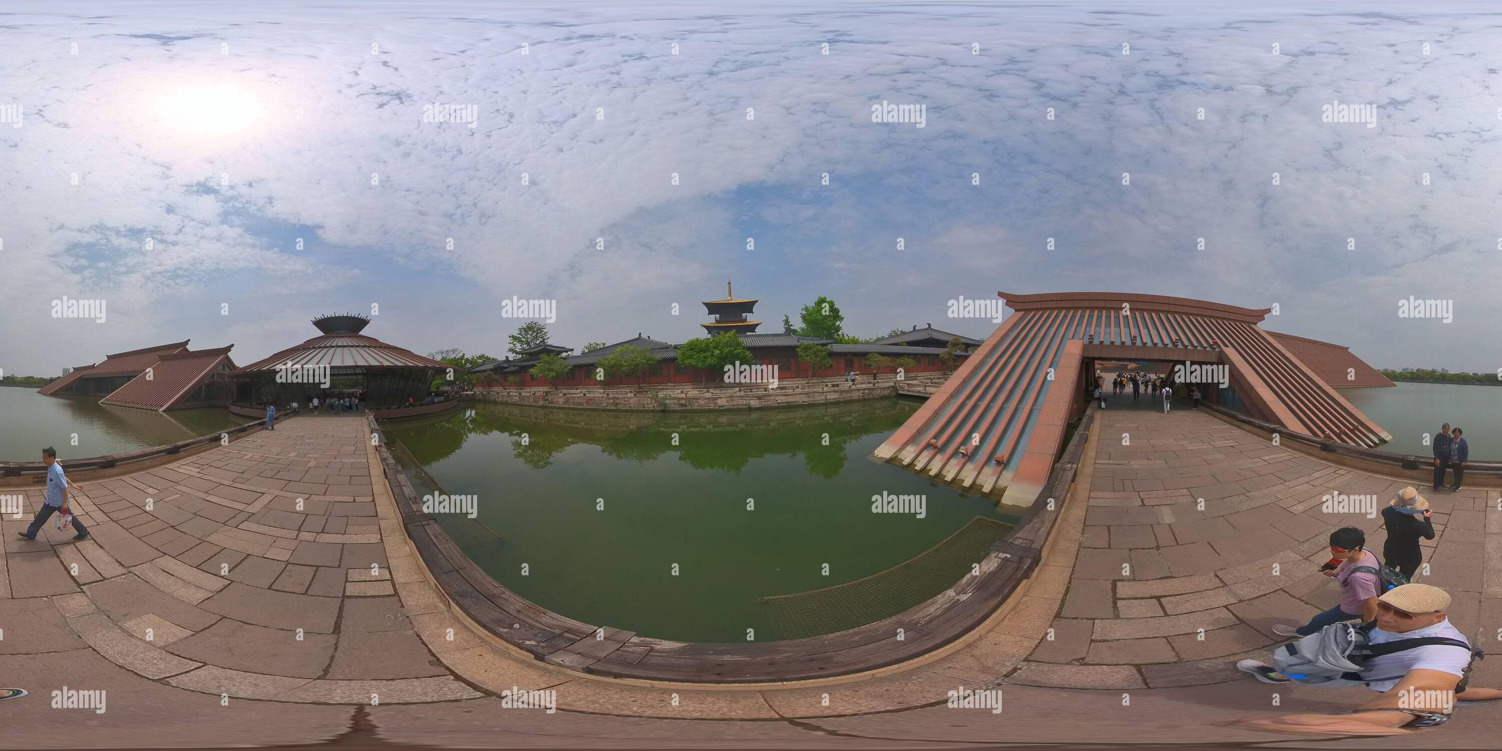 Visualizzazione panoramica a 360 gradi di 360 vedute dei visitatori camminano attraverso un moderno edificio con tetto inclinato sull'acqua, che mescola architettura tradizionale e contemporanea