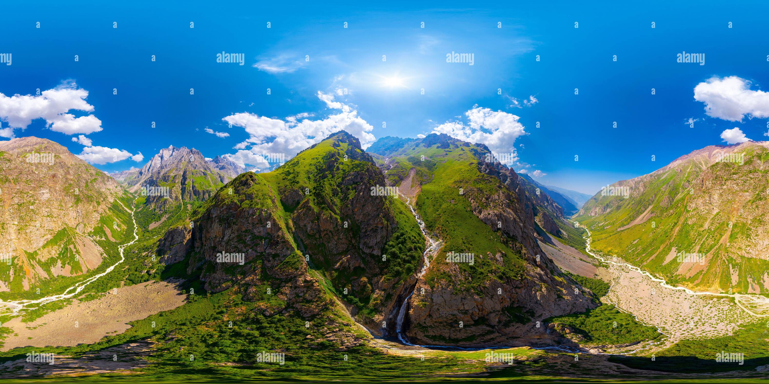 Visualizzazione panoramica a 360 gradi di Le vette frastagliate e ricoperte di verde si innalzano maestosamente su un fiume tortuoso. La vegetazione lussureggiante e le nuvole spettacolari esaltano la bellezza serena di questa padella
